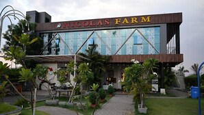 A building with a sign reading 'NICOLAS FARM' and a paved entrance area with potted plants. - Nicolas Farm & Resort (Parsivni)