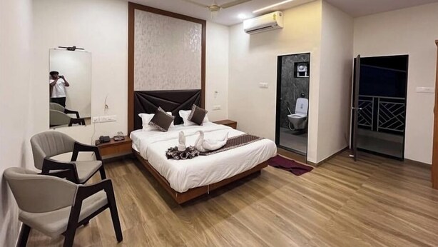 A modern hotel room with a bed, a chair, a mirror, an air conditioning unit, and a door leading to a balcony. - Nicolas Farm & Resort (Parsivni)