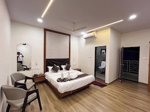 Ett modernt hotellrum med en säng, en stol, en spegel, en luftkonditioneringsanläggning och en dörr som leder ut till en balkong.