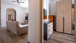 Una sala de estar moderna con sofá, ventilador de techo y área de cocina con armarios y refrigerador.