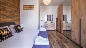 Un dormitorio moderno con pared de madera, un espejo grande, una cama con almohadas, una mesita de noche y una lámpara colgante.