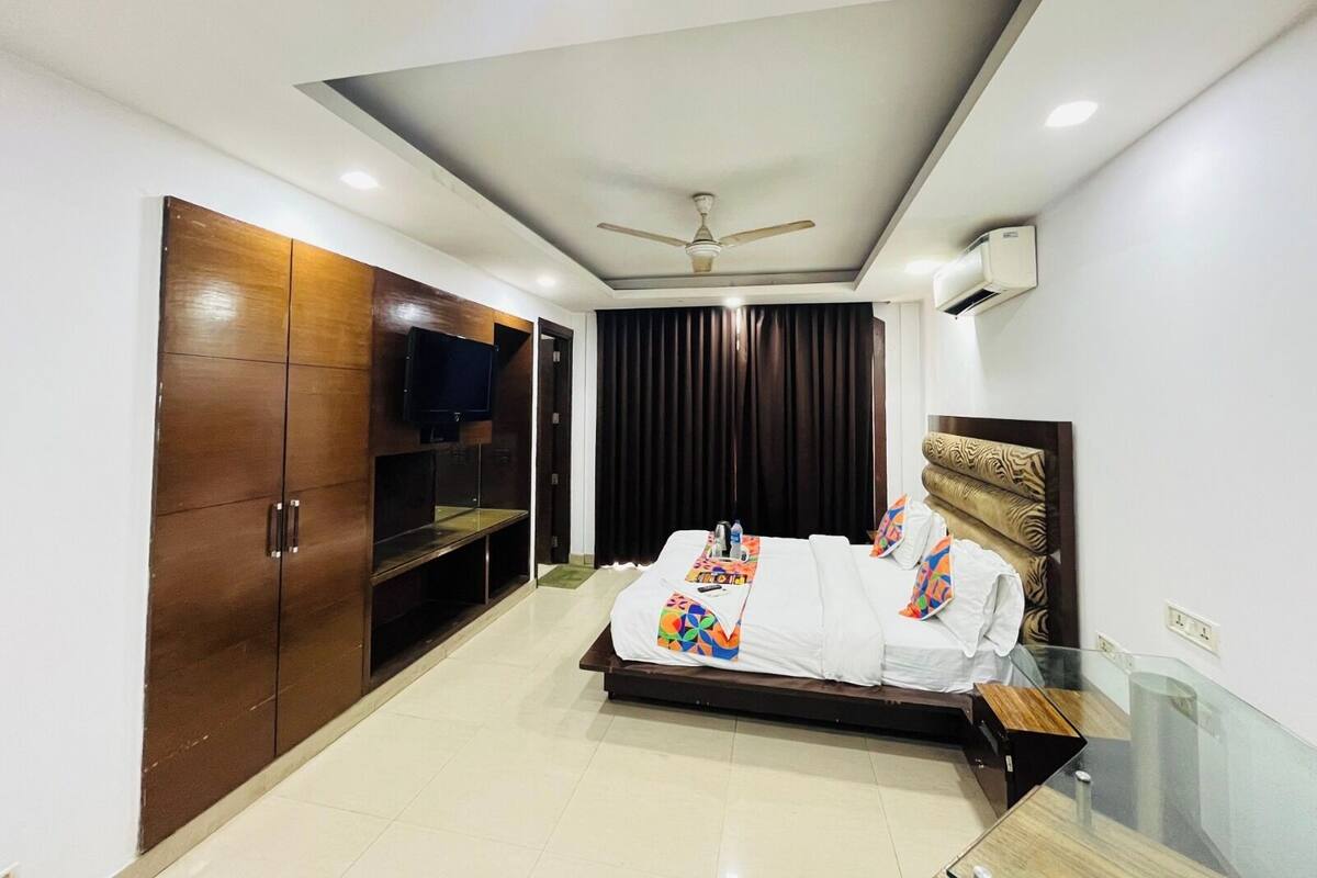 Una habitación de hotel moderna con cama, televisor, ventilador de techo y armario.