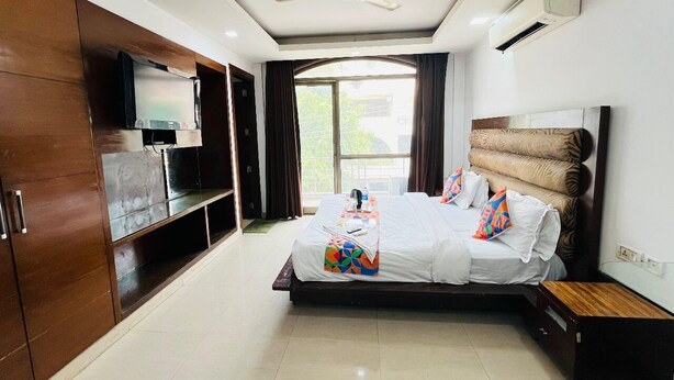 Una habitación de hotel moderna con una cama grande, un ventilador de techo, un equipo de aire acondicionado y un televisor en la pared.