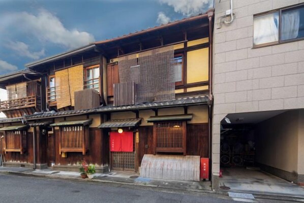 A traditional Japanese building with multiple wooden floors, sliding doors, and a red awning. - Nijo-ouan (Kyoto)