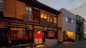 A traditional Japanese building with a red entrance, wooden balconies, and a modern structure adjacent to it. - Nijo Ohan (Kyoto)