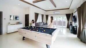 A modern living room with a pool table, a sofa, and a television. - Destiny Pool Villa (Bang Lamung)