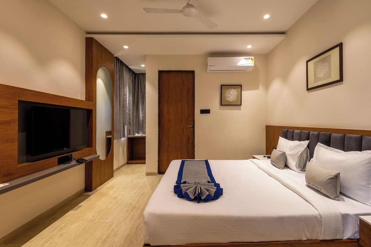 A hotel room with a bed, a TV, a ceiling fan, and an air conditioning unit.