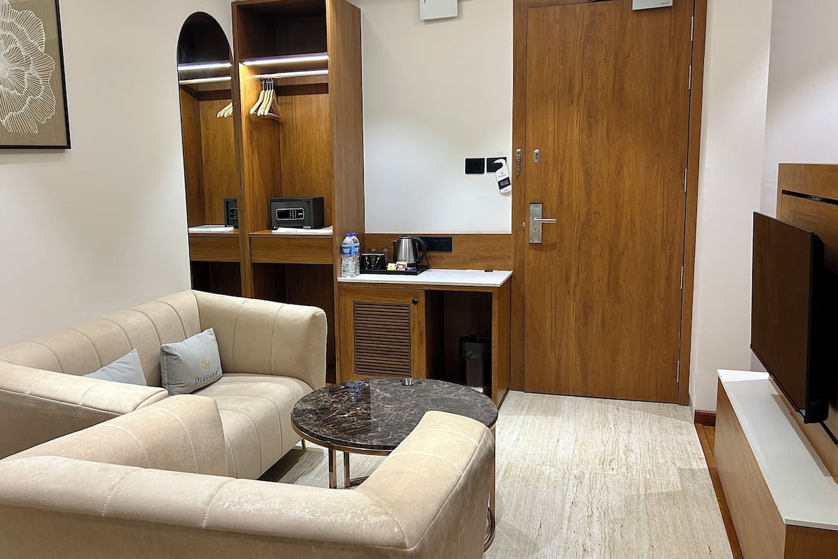A modern living room with a beige sofa, a small round table, and a wooden cabinet with a mirror.