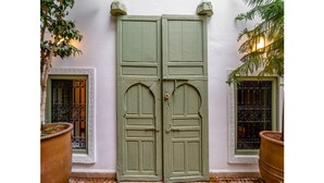 A green door with a white frame, flanked by two potted plants. - Luxury and super-stylish riad in the heart of Marrakech Médina, fully staffed (Marrakech)