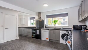 A modern kitchen with grey cabinets, a dishwasher, a built-in oven, and a microwave. - 9 Monks Crescent (Durham)