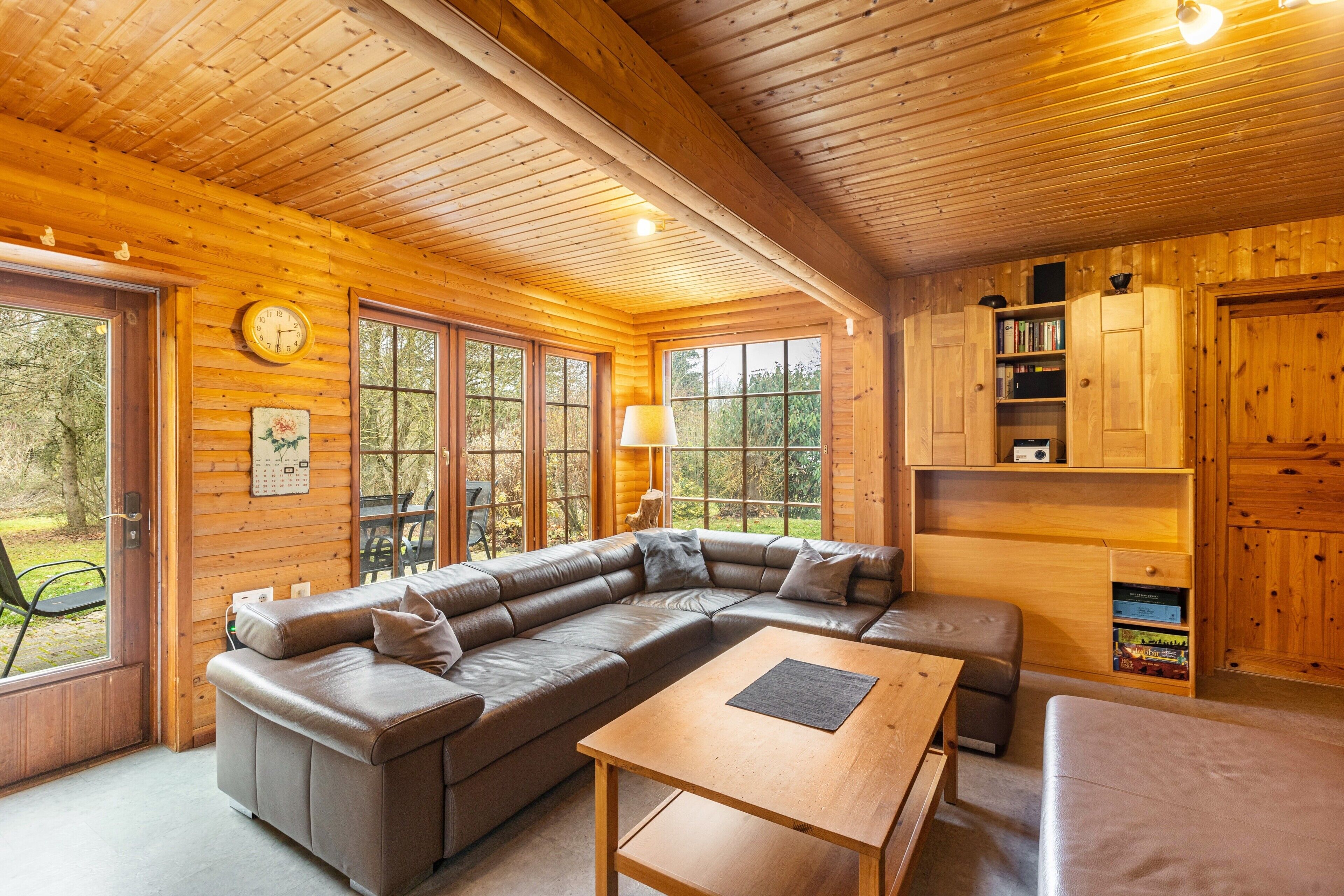 Ein Holzinterieur mit einem Ecksofa, einem Holztisch und einem Bücherregal.
