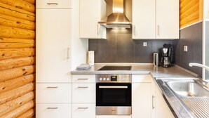 A modern kitchen with white cabinetry, a stainless steel range hood, a built-in oven, and a coffee maker.