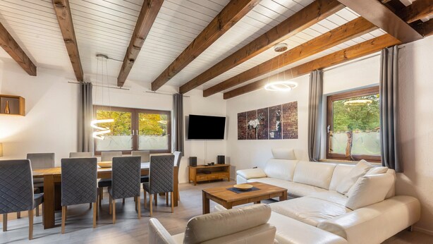 En moderne stue med sofa, spisebord, stole og fjernsyn.