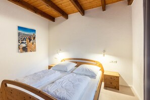 Une chambre à coucher avec un lit en bois, deux tables de chevet et un tableau accroché au mur.