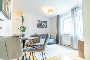 Un salon moderne comprenant un coin repas, un canapé, une table basse et une grande fenêtre avec des rideaux.
