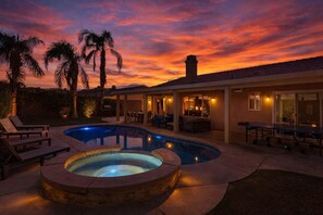 Una piscina con hidromasaje, sillas de descanso y un patio con mobiliario exterior.