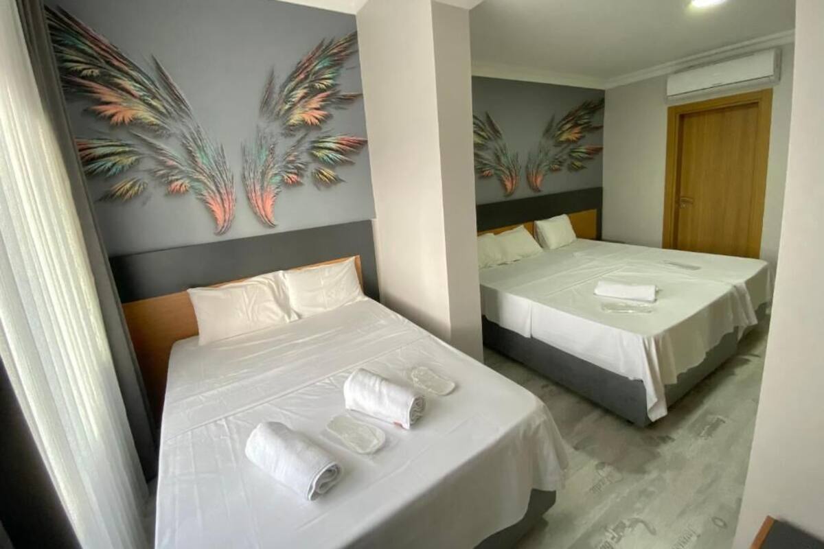 A hotel room with two beds, a wooden door, and decorative wall art.