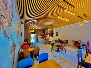 A modern restaurant interior with wooden ceiling slats, hanging light fixtures, and colorful chairs. - Viktoryus Otel (Istanbul)