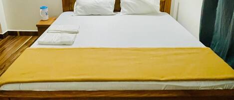 A single bed with a wooden frame, white bedding, and a yellow blanket.