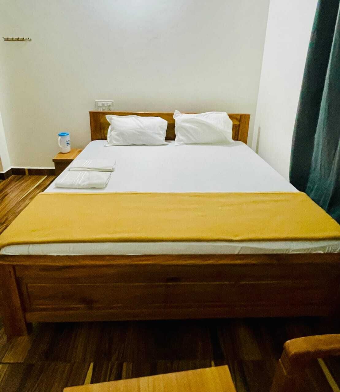 A neatly made bed with a yellow blanket, white pillows, and a wooden headboard.