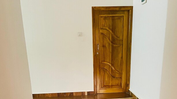 A hallway with wooden flooring and a wooden door. - Murdeshwar Comforts (Murudeshwara)
