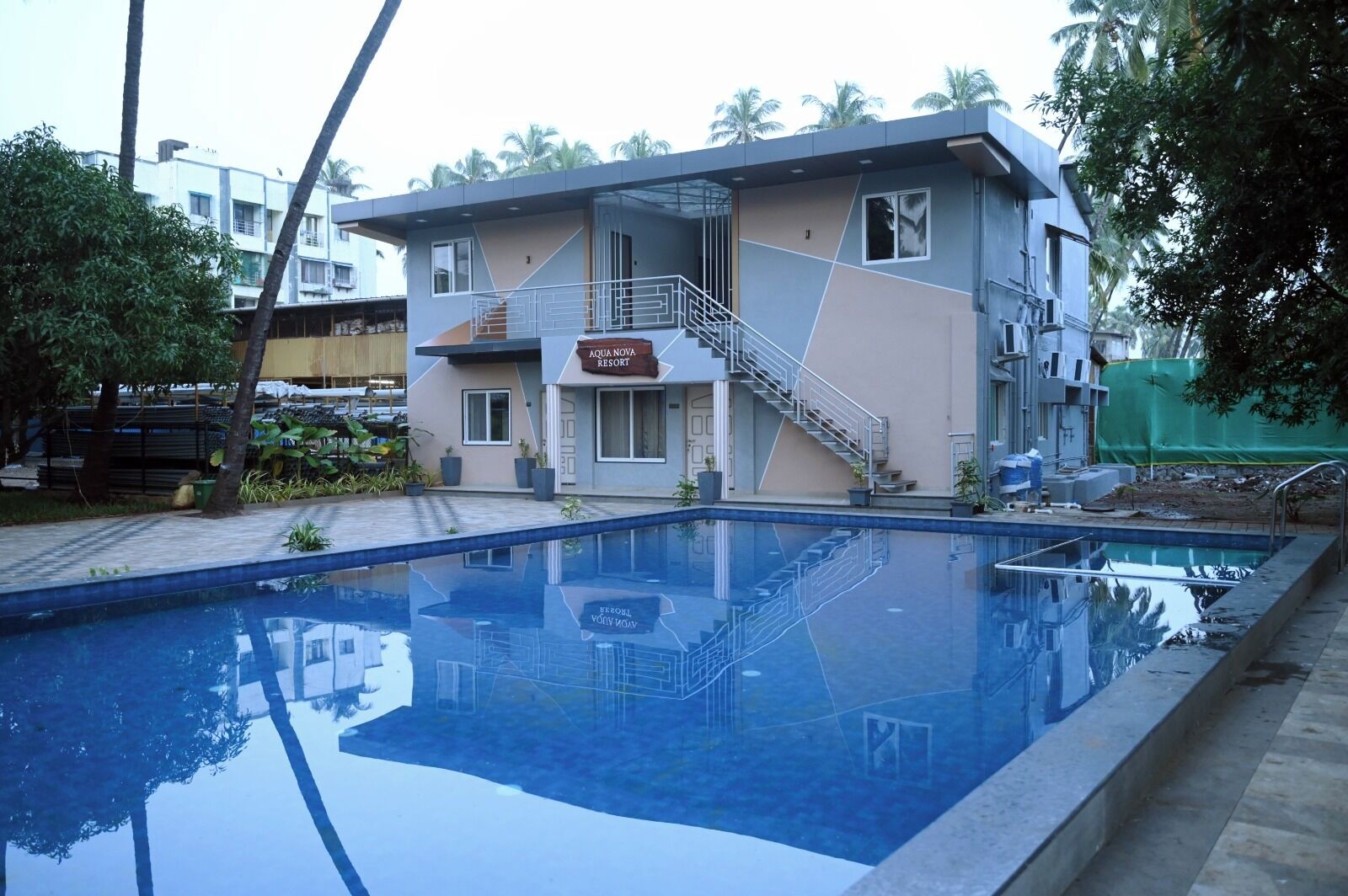 Un bâtiment moderne avec une enseigne indiquant « AQUA NOVA RESORT » et une piscine au premier plan.