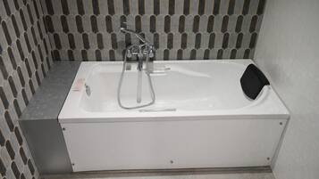 A white bathtub with a handheld showerhead and a black seat.
