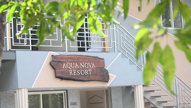 En skylt för Aqua Nova Resort med en modern arkitektonisk design, inklusive en trappa och en balkong.