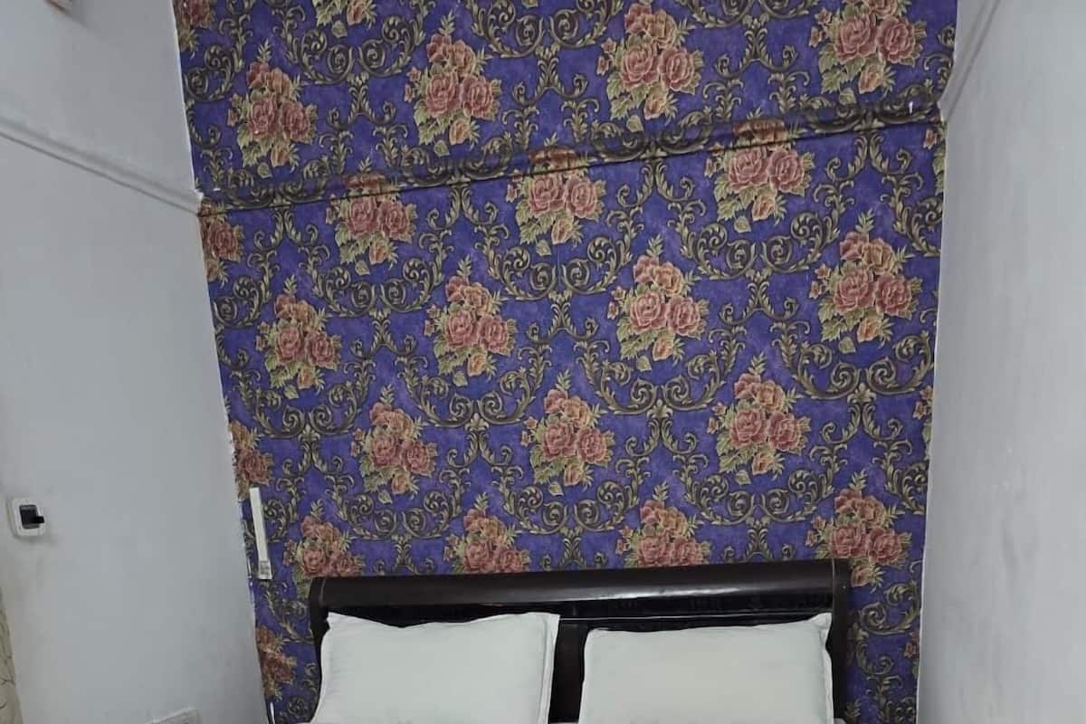 A bed with a white mattress and a floral-patterned headboard.