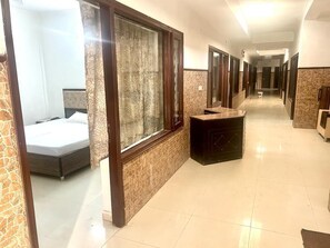 A hotel corridor with a bed, a vanity, and a mirror. - Poonam Villas (New Delhi)