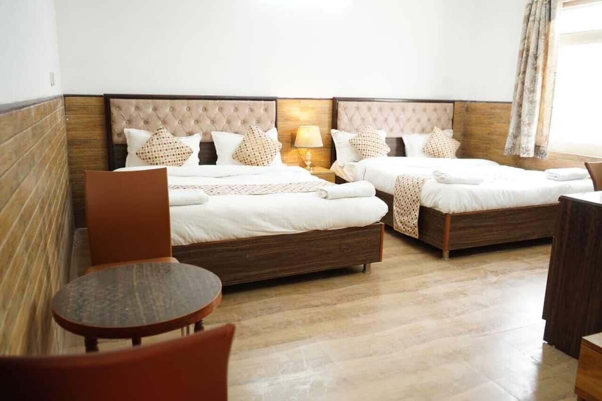 A hotel room with two beds, a small table, and a chair.