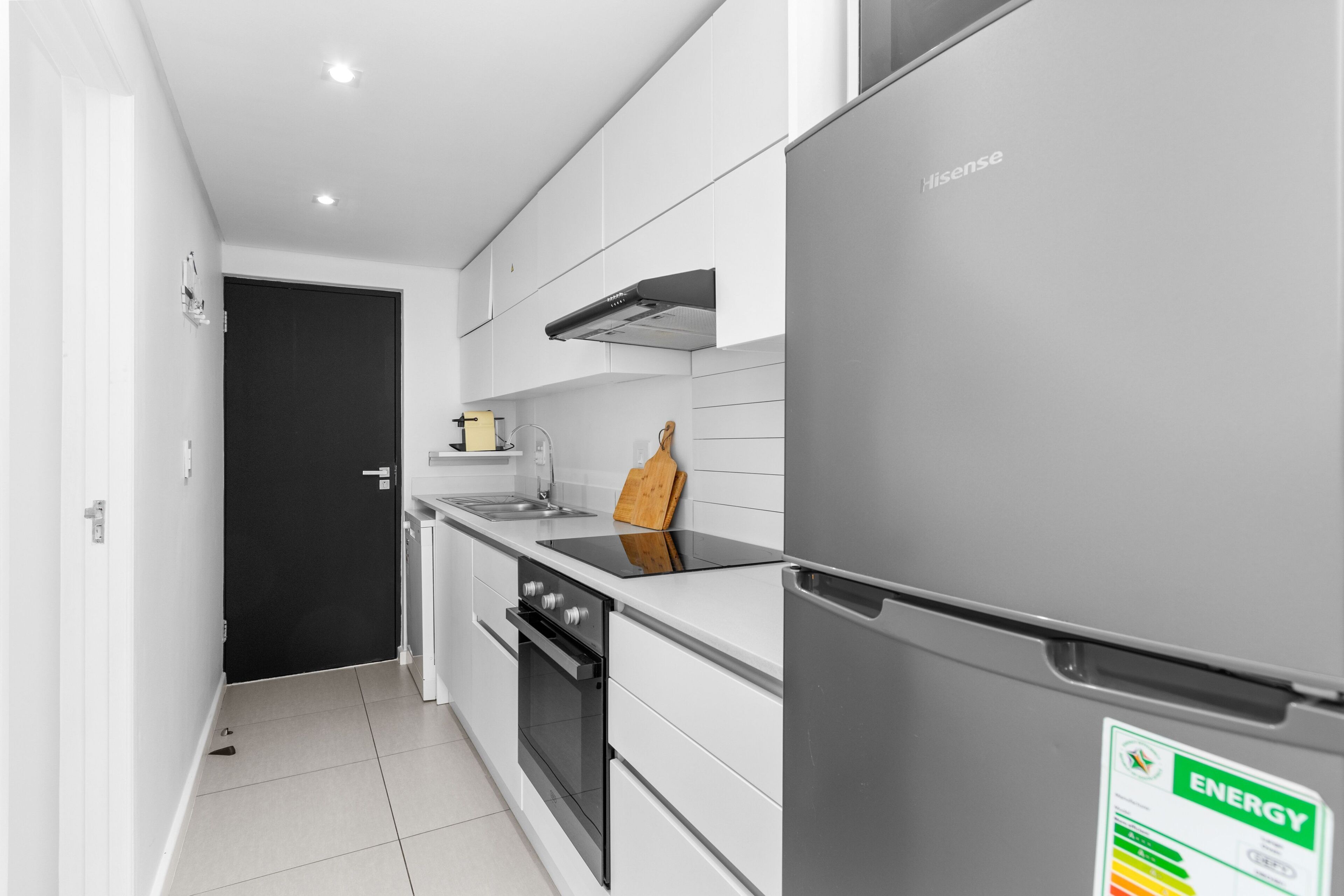 A modern kitchen with a stainless steel refrigerator, a built-in oven, and a black door.