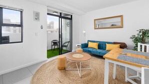 Un salon moderne avec un canapé bleu, une table basse en bois et une grande fenêtre.