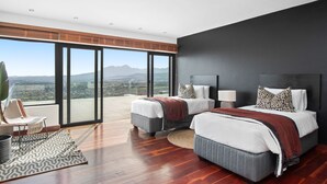 A modern bedroom with two beds, large windows, and a view of the city. - Restio View 11 (Cape Town)