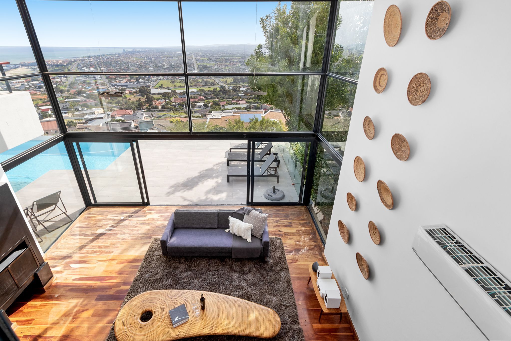 A modern living room with a large glass wall, a pool, and a view of a cityscape.