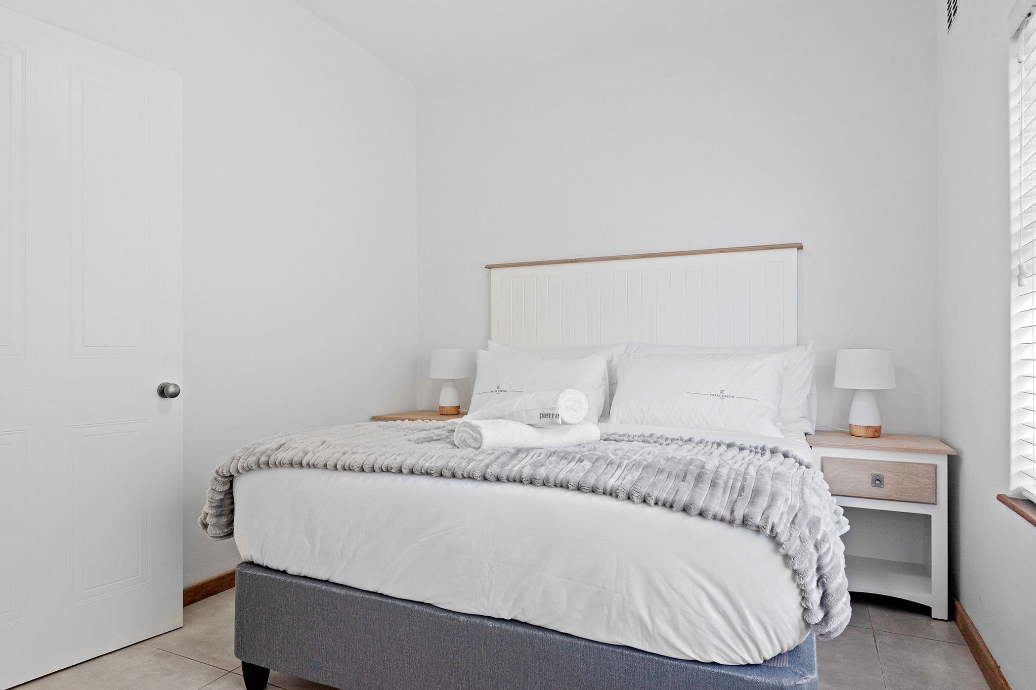 Une chambre à coucher bien rangée, avec un lit, des tables de chevet et une porte.