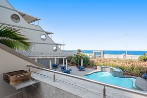 A poolside area with a barbecue grill, outdoor seating, and a view of the ocean. - Perna Perna Coastal Escape (eMdloti)