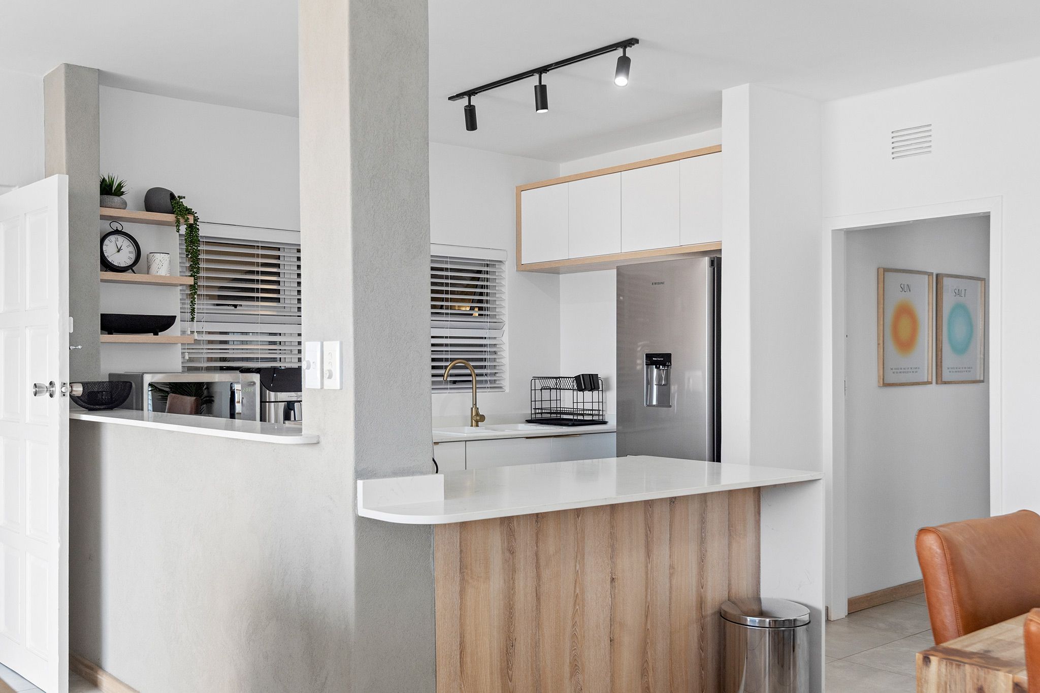 A modern kitchen with white cabinetry, a wooden island, and built-in appliances.