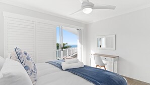 Ein Schlafzimmer mit einem Bett, einem Schreibtisch und Meerblick.