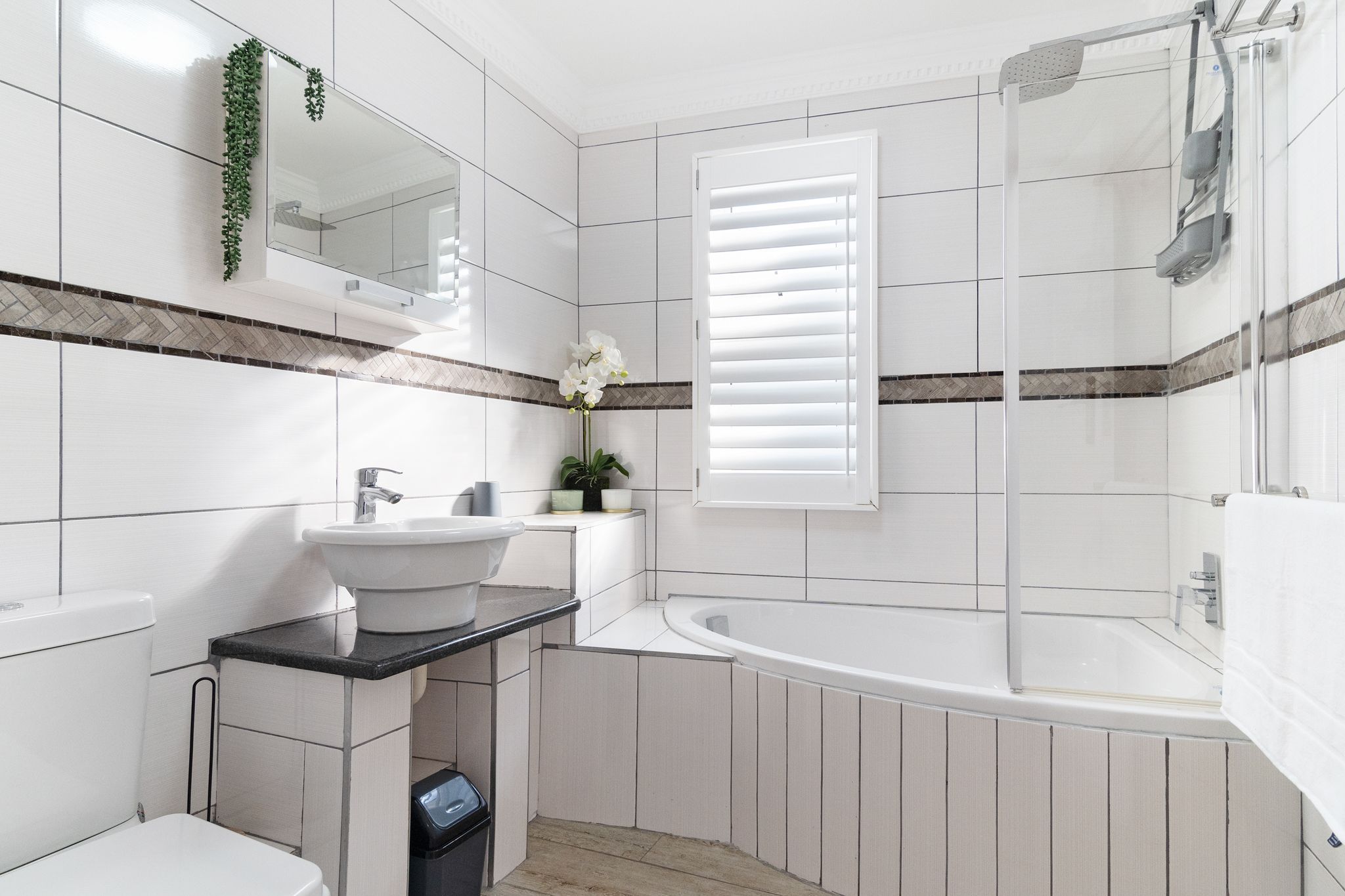 A modern bathroom with a white sink, vanity, and bathtub.