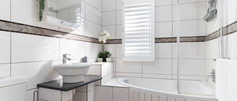 A modern bathroom with a white sink, vanity, and bathtub.