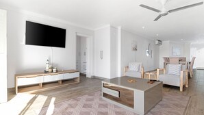 Ein modernes Wohnzimmer mit Flachbildfernseher, Deckenventilator und Couchtisch aus Holz.