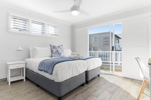 A bedroom with a bed, nightstand, and a view of the outside balcony. - San Marino 17 (Ballito)