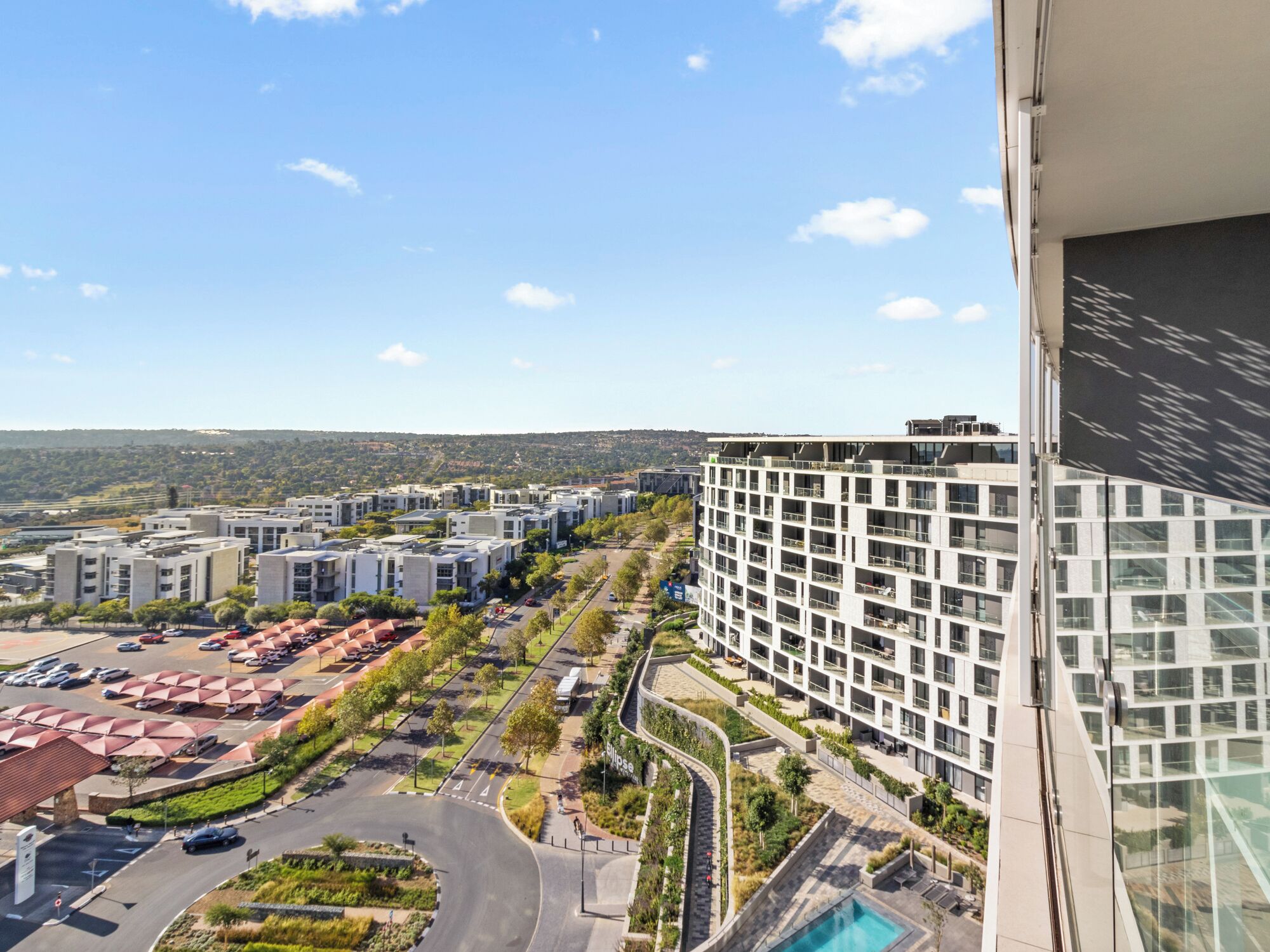 Un complesso residenziale moderno con diversi edifici, un'area parcheggio e una piscina.