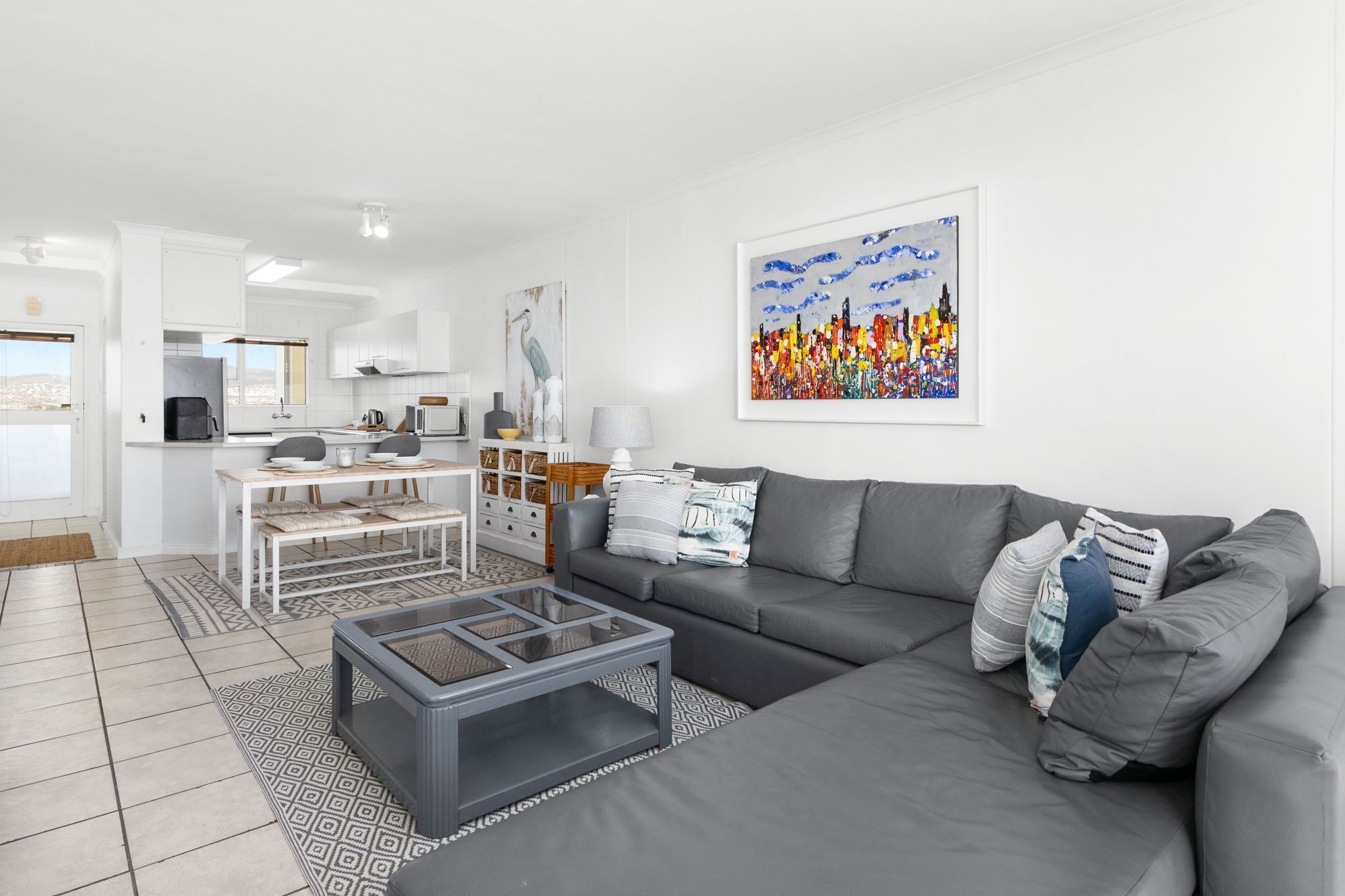 Ein modernes Wohnzimmer mit einem grauen Sofa, einem Couchtisch und einem Stadtbild.