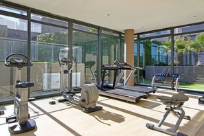 A gym with cardio machines, weight machines, and dumbbells.