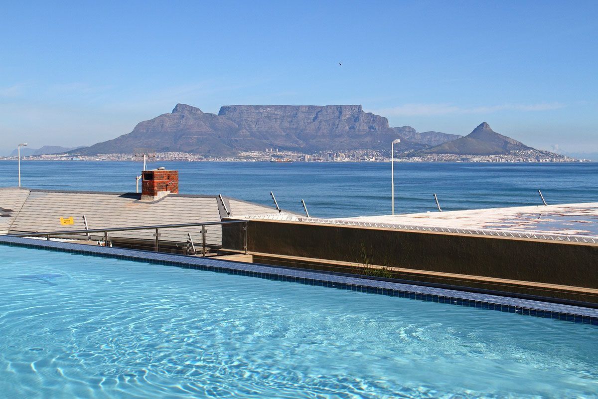A swimming pool with a view of a mountain and a cityscape in the background.