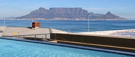 A swimming pool with a view of a mountain and a cityscape in the background.