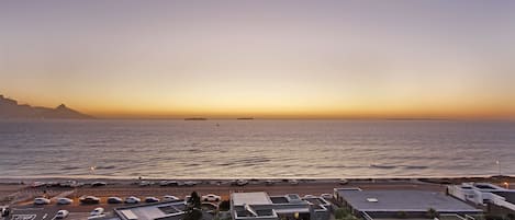 A coastal view with a parking area and buildings in the foreground.