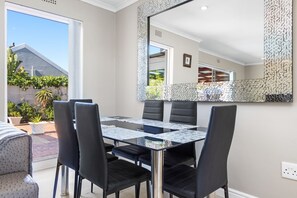 A dining area with a glass table, black chairs, and a large mirror on the wall.